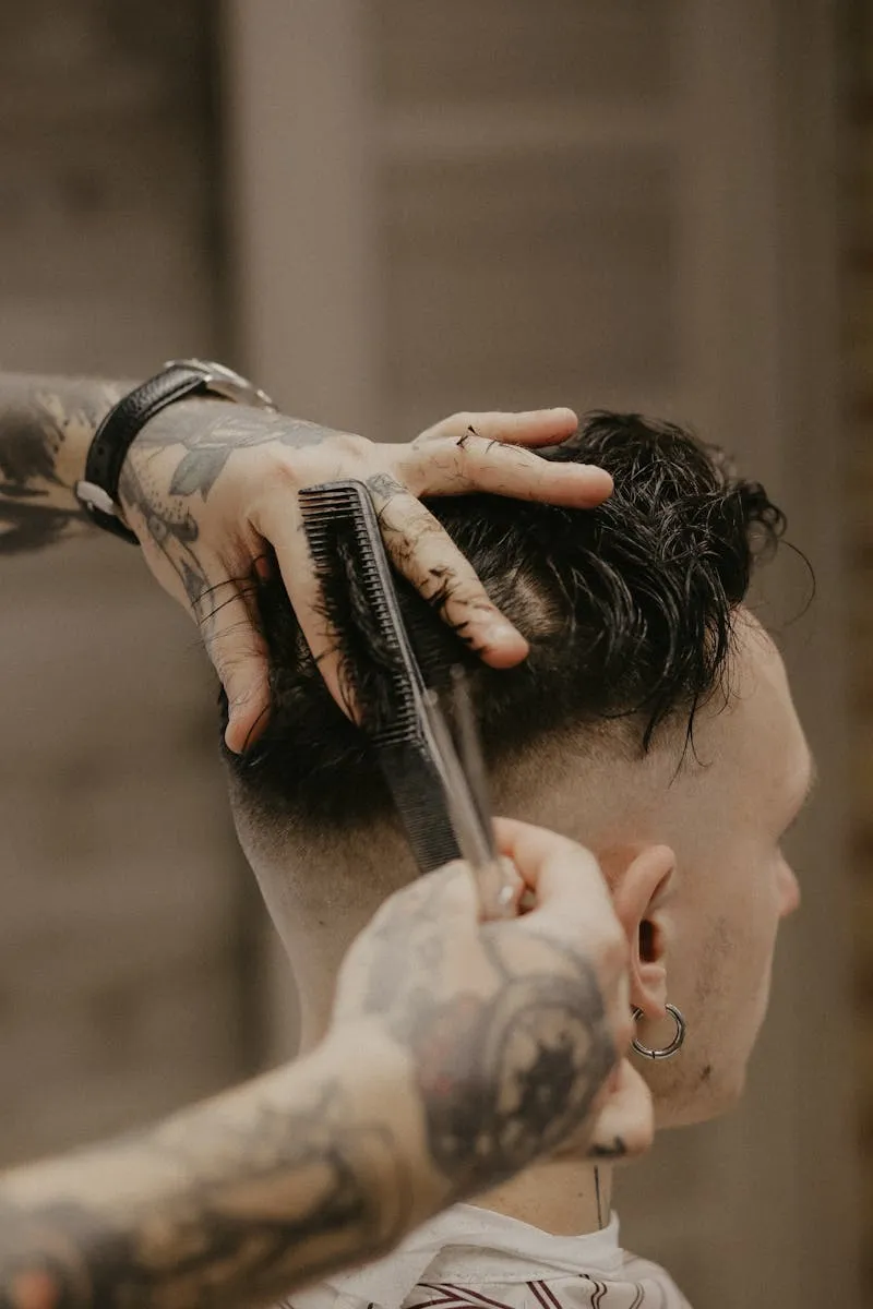 Barbero con manos tatuadas cortando con tijera